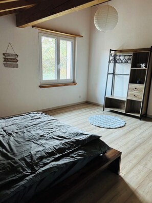 A bedroom with a bed, a window, a wardrobe, and a hanging light fixture.