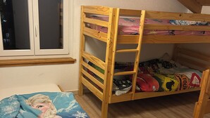 Un letto a castello con una finestra e un letto con coperta a tema Frozen.