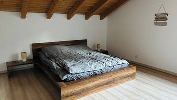 Ein Schlafzimmer mit einem hölzernen Bettgestell, einem Nachttisch mit Lampe und einem an der Wand befestigten Schild.