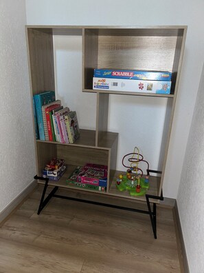 Ein Holzbücherregal mit verschiedenen Gesellschaftsspielen und Puzzles.