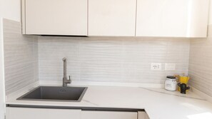 A kitchen with white cabinets, a black sink, and a tiled backsplash. - Sunset Panorama - Two Bedroom Apartment, Sleeps 4 (Alghero)