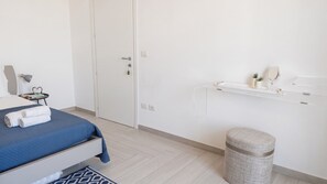 A bedroom with a bed, bedside table, lamp, and a small stool. - Sunset Panorama - Two Bedroom Apartment, Sleeps 4 (Alghero)