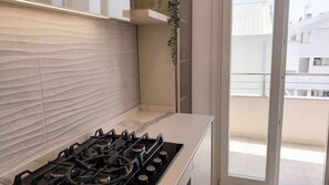 Une cuisine moderne équipée d’une cuisinière à gaz, de carreaux blancs et offrant une vue sur la ville grâce à une grande fenêtre.