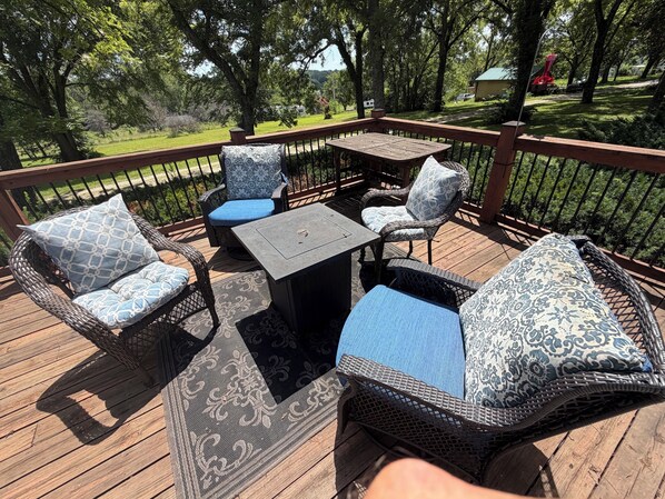 A deck with wicker furniture, a table, and chairs with patterned cushions.