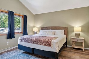A bedroom with a bed, two bedside tables, a window with curtains, and a view of greenery outside. - Dog Friendly Home in Sturgeon Bay with fire pit (Sturgeon Bay)