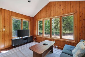A room with wooden walls, a flat-screen TV, a wooden coffee table, and a sofa. - Dog Friendly Home in Sturgeon Bay with fire pit (Sturgeon Bay)