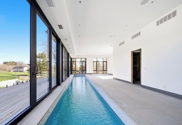 Una piscina interior moderna con amplios ventanales y vistas al exterior.