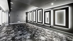 Habitació d'hotel amb una àmplia zona amb moqueta, llums encastades al sostre i una paret amb panells il·luminats.