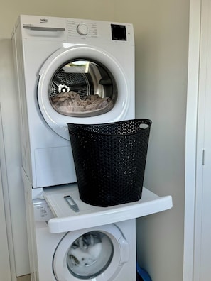 Eine Waschmaschine mit Frontlader, Bedienfeld und einem Trockner darunter.