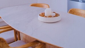 Een moderne keuken met witte kasten, een houten aanrecht en een eettafel met stoelen.
