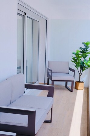 A modern outdoor seating area with a sofa and a chair, a potted plant, and a sliding glass door. - Swallows' Refuge | Monte Gordo (Monte Gordo)