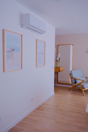 Ein Zimmer mit Holzboden, einem blauen Stuhl und gerahmten Bildern an der Wand.