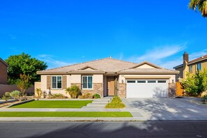 Une maison de plain-pied avec un garage, une pelouse bien entretenue et un ciel bleu dégagé.