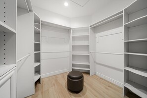 Un placard d’angle avec des étagères ouvertes et un tabouret rond.