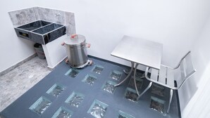 Ein Badezimmer mit Fliesenboden, Waschbecken, Mülleimer und Duschbereich.