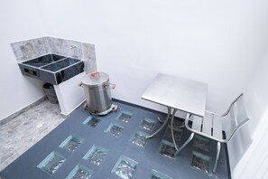Ein Badezimmer mit Fliesenboden, Waschbecken, Mülleimer und Duschbereich.