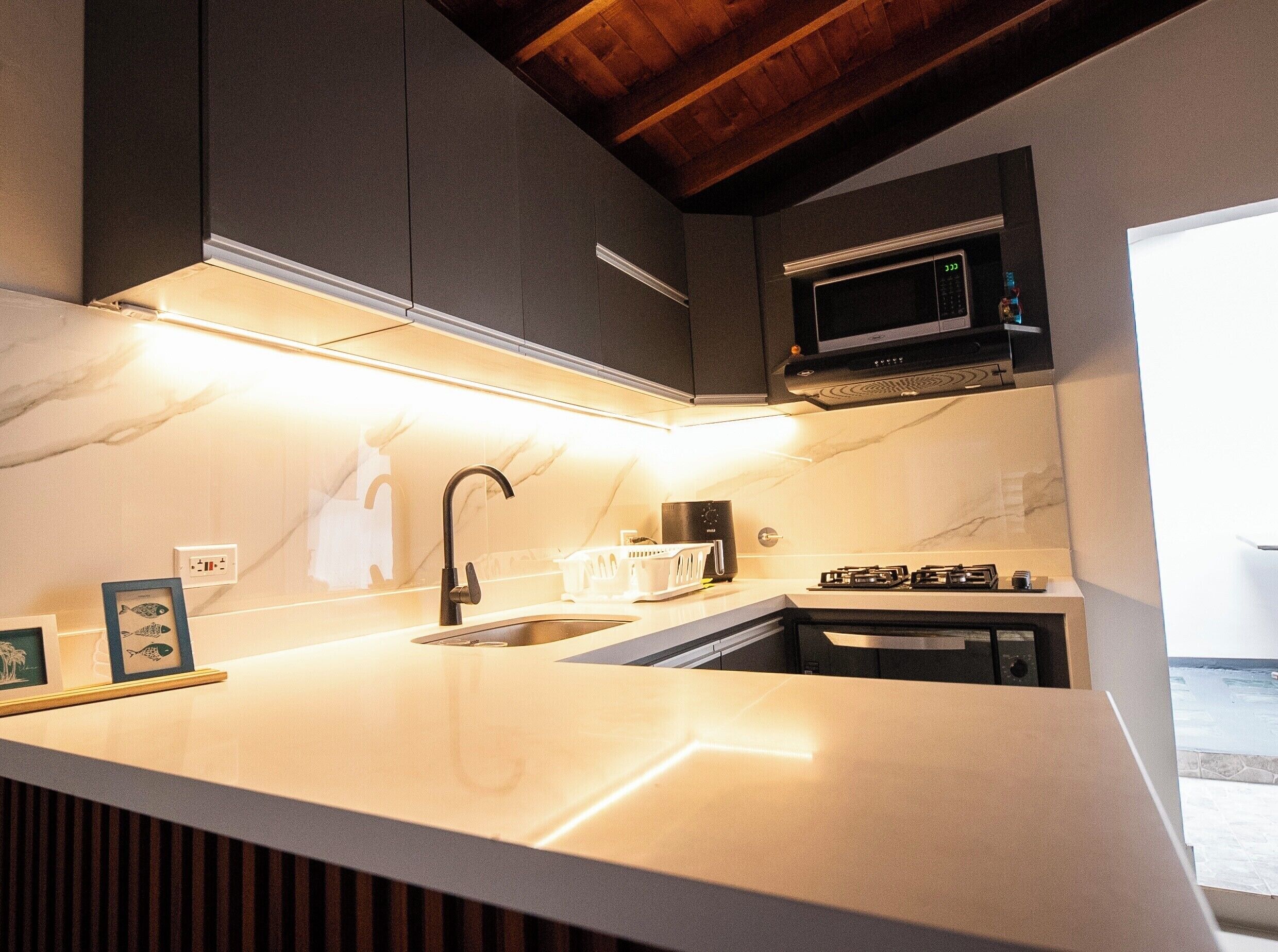 A modern kitchen with a white countertop, a built-in microwave, and a sink.