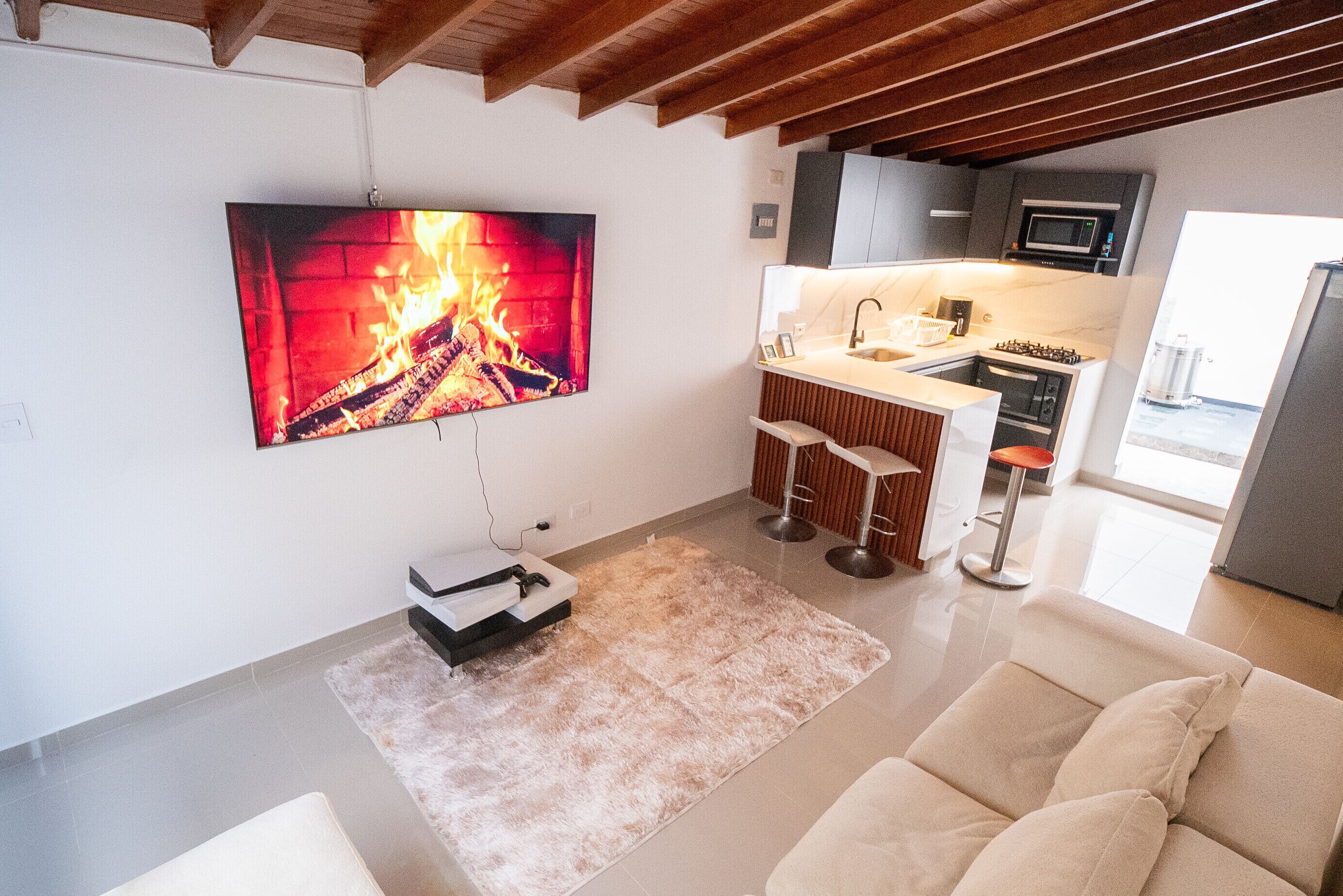 Een moderne woonkamer met een flatscreen televisie aan de muur, een bank, een salontafel en een open haard.
