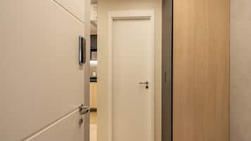 Un pasillo con una puerta blanca, una puerta de madera y un picaporte metálico.