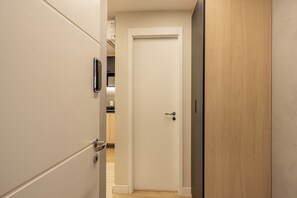 Un pasillo con una puerta blanca, una puerta de madera y un picaporte metálico.