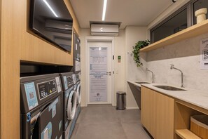 Zona de lavandería con lavadoras, un lavabo y una puerta con instrucciones de uso.