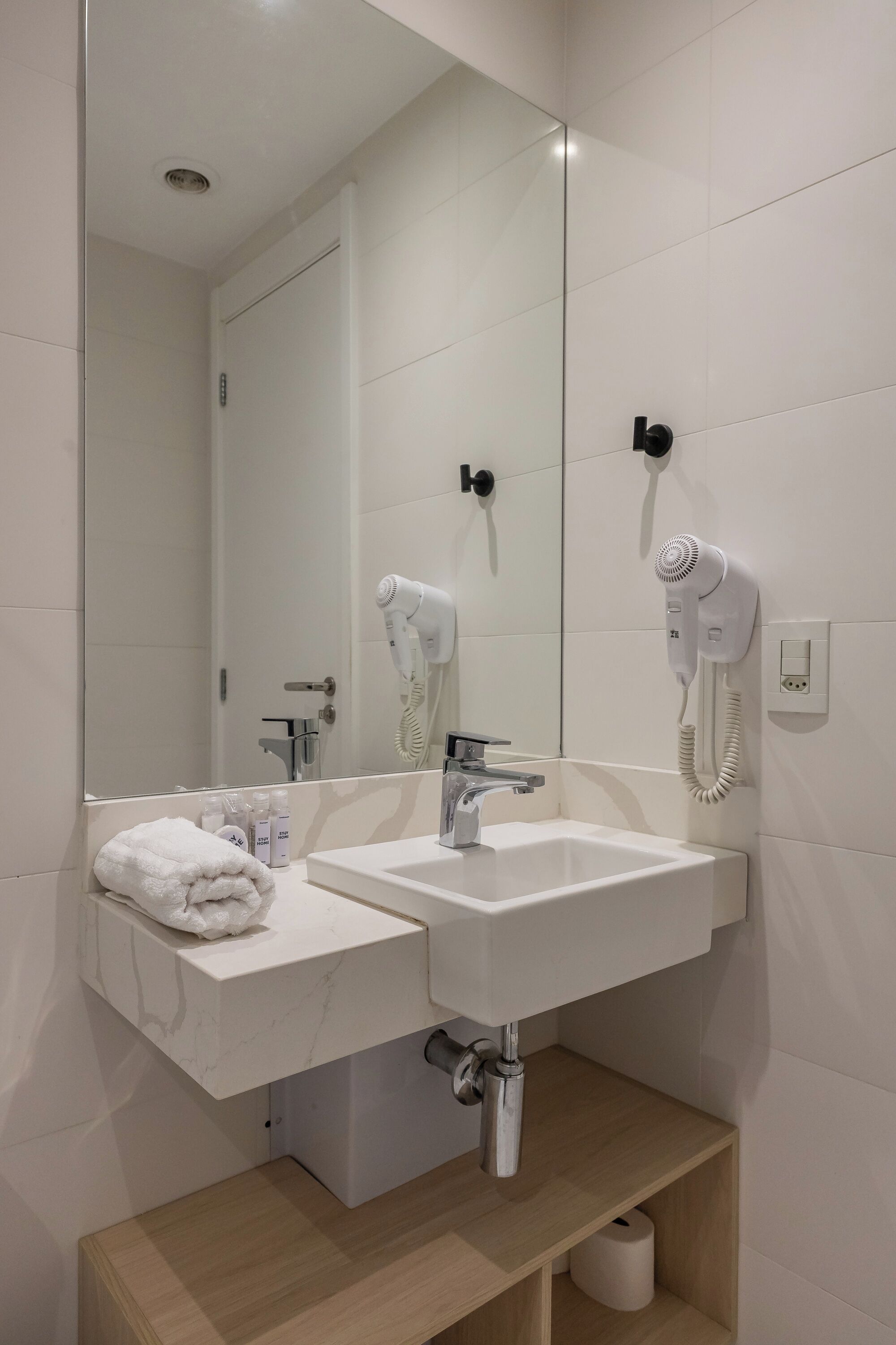 Ein modernes Badezimmer mit einem Doppelwaschbecken, einem Spiegel, einem Handtuchhalter und einem Fön.