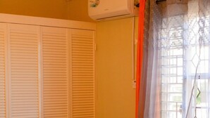 A bedroom with a bed, a window with curtains, and a closed door. - Sumfest ~ Draxhall ~ 24hr Gated ~ Pool (St Ann Jamaica)