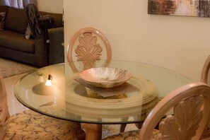 Uma mesa de vidro redonda com uma tigela decorativa e uma pequena fonte de luz.