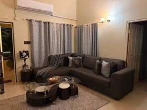 A living room with a sectional sofa, a glass coffee table, and a dark rug. - Sumfest ~ Draxhall ~ 24hr Gated ~ Pool (St Ann Jamaica)