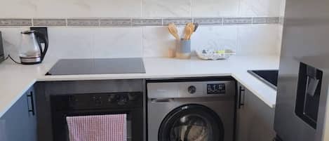 A compact kitchen with a built-in washer and dryer, a coffee maker, and a microwave.