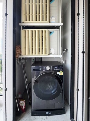 Ein kleiner Hauswirtschaftsraum mit einer LG Waschmaschine, einem Trockner und einem Wäscheständer.