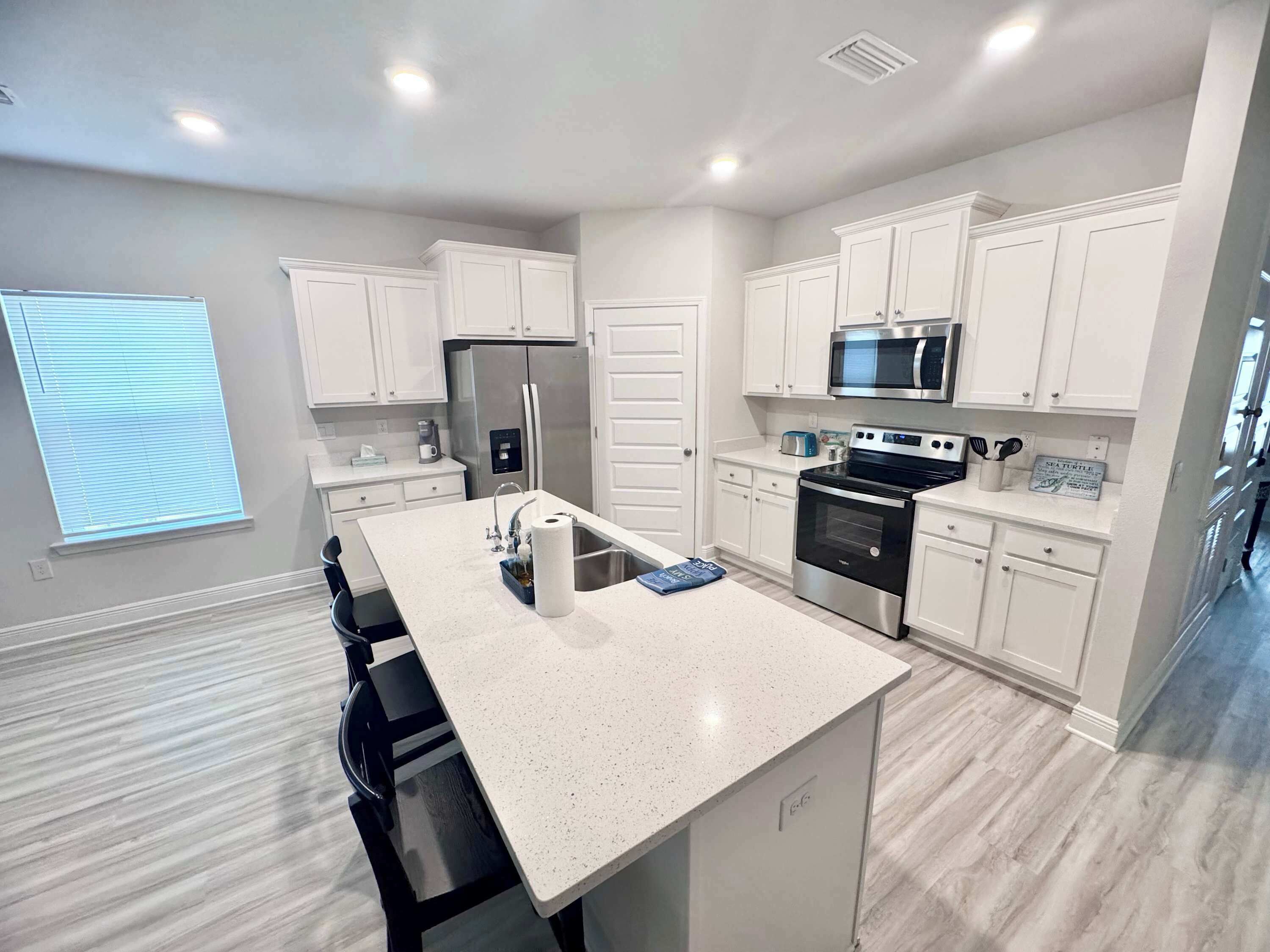 A modern kitchen with white cabinetry, stainless steel appliances, and a central island.