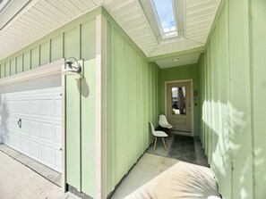 A garage door, a door with a glass panel, a chair, and a small step leading to a porch. - Coastal Escape in Sea Grove (Port St. Joe)
