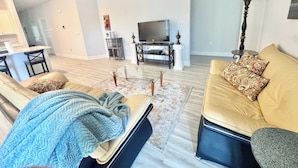 A living room with a sofa, a coffee table, and a television. - Coastal Escape in Sea Grove (Port St. Joe)