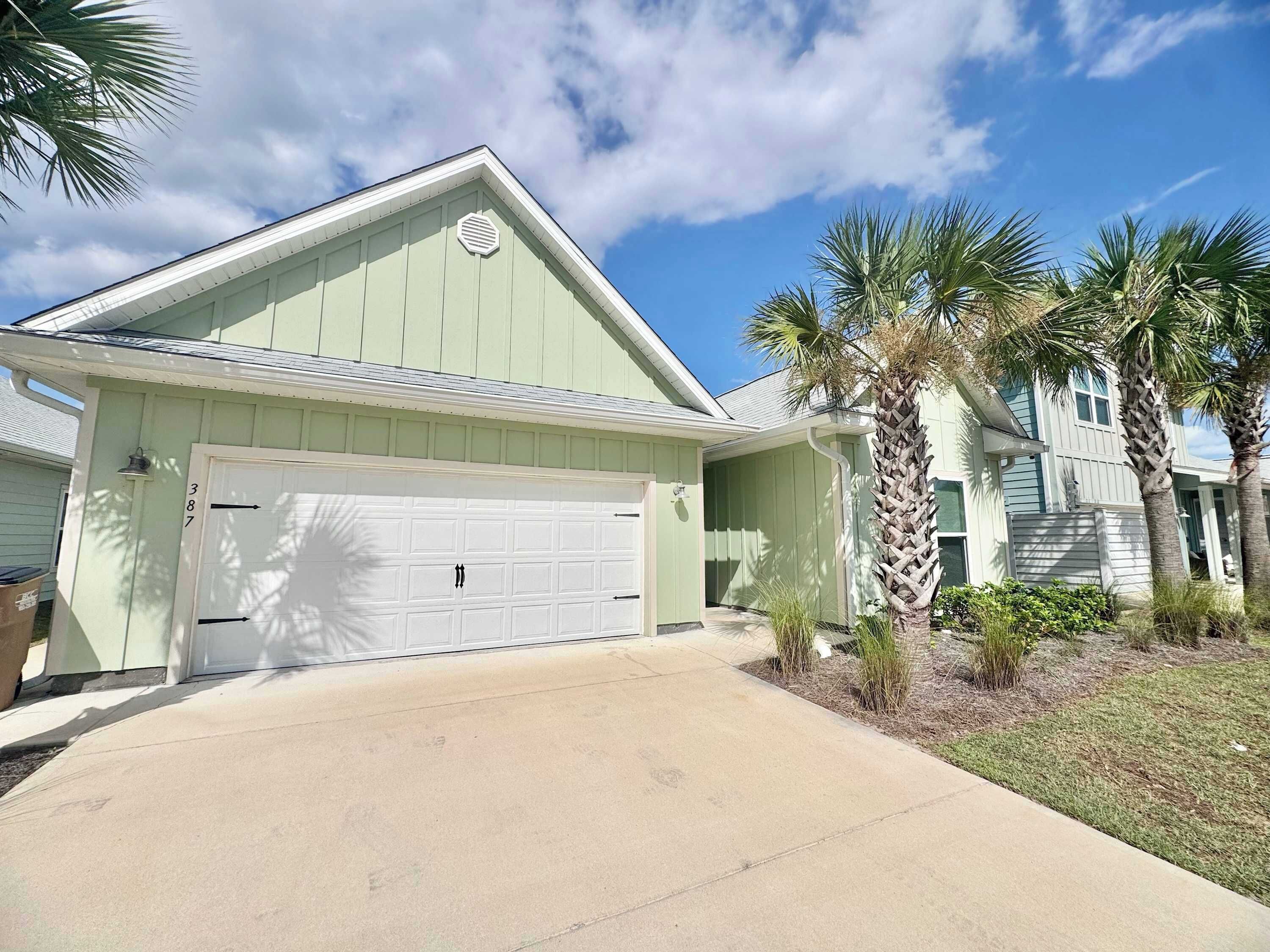 A single-story house with a garage, a light green exterior, and a clear sky.