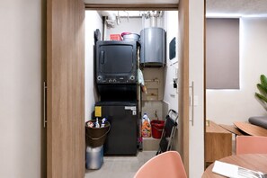 Eine kompakte Küche mit Waschmaschine, kleinem Kühlschrank und einer Essecke mit Tisch und Stühlen.