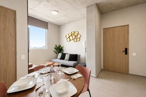A dining area with a table set for four, a grey sofa, and a decorative wall piece. - ¡A pasos de Fundidora! 5 huéspedes, Seguridad 24/7 (Monterrey)