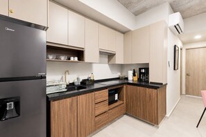 Una cocina moderna con un refrigerador negro, armarios de madera, una encimera negra y una cafetera.