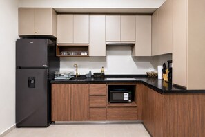 A kitchen with a black refrigerator, wooden cabinets, a microwave, and a coffee maker. - ¡A pasos de Fundidora! 5 huéspedes, Seguridad 24/7 (Monterrey)