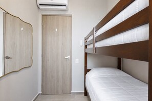 Ein Zimmer mit Holztür, Etagenbett und Klimaanlage.