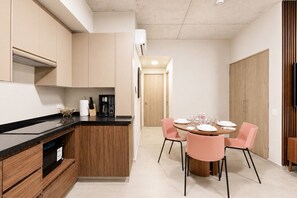 A modern kitchen with a central island, wooden cabinets, and a dining area with pink chairs and a round table. - ¡A pasos de Fundidora! 5 huéspedes, Seguridad 24/7 (Monterrey)