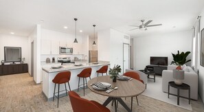 A modern kitchen with a central island, bar stools, and a dining table with chairs. - Walk to the Brickyard 400! 2BR/2BA Apartment in Speedway, IN! (Speedway)