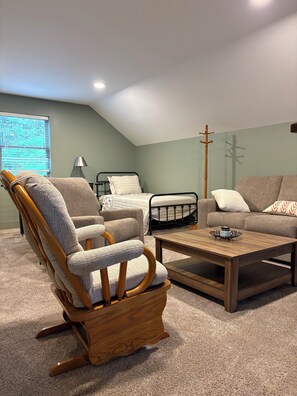A cozy room with a wooden rocking chair, a sofa, a bed, and a coffee table.