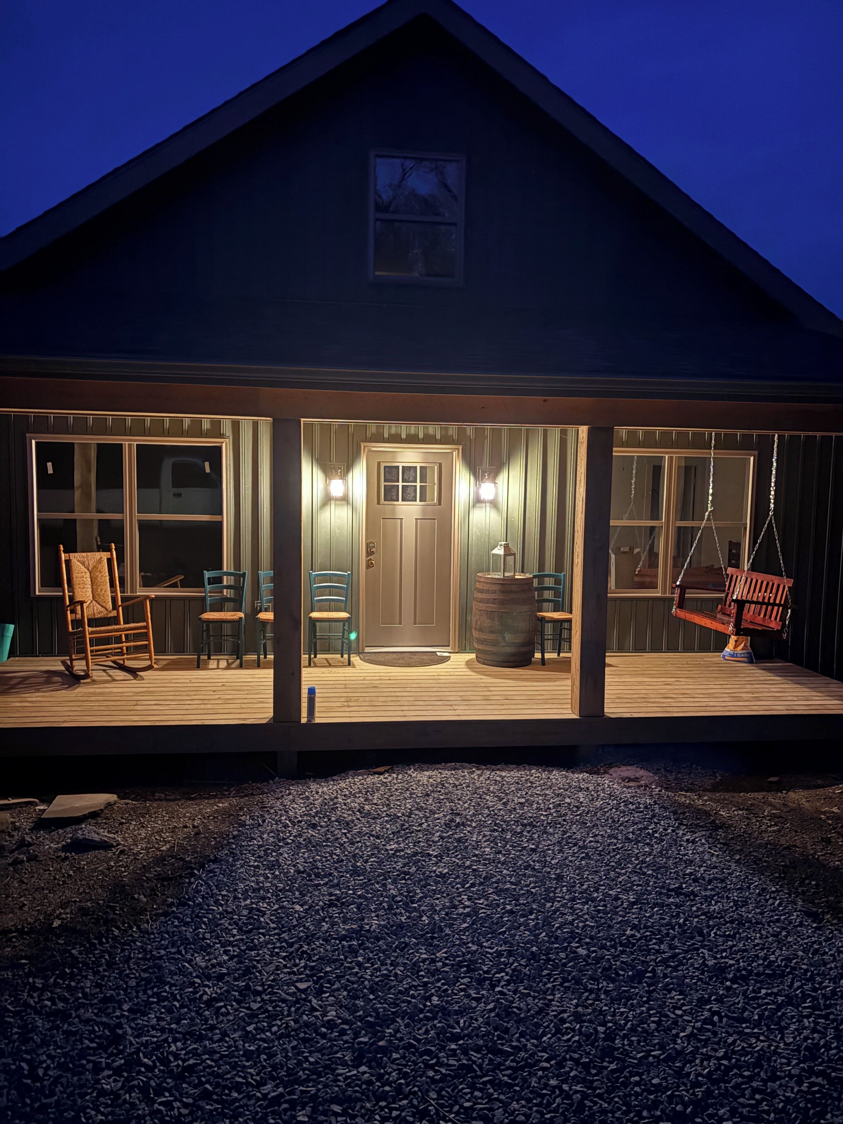 A wooden house with a porch, a swing, and a door with a window.
