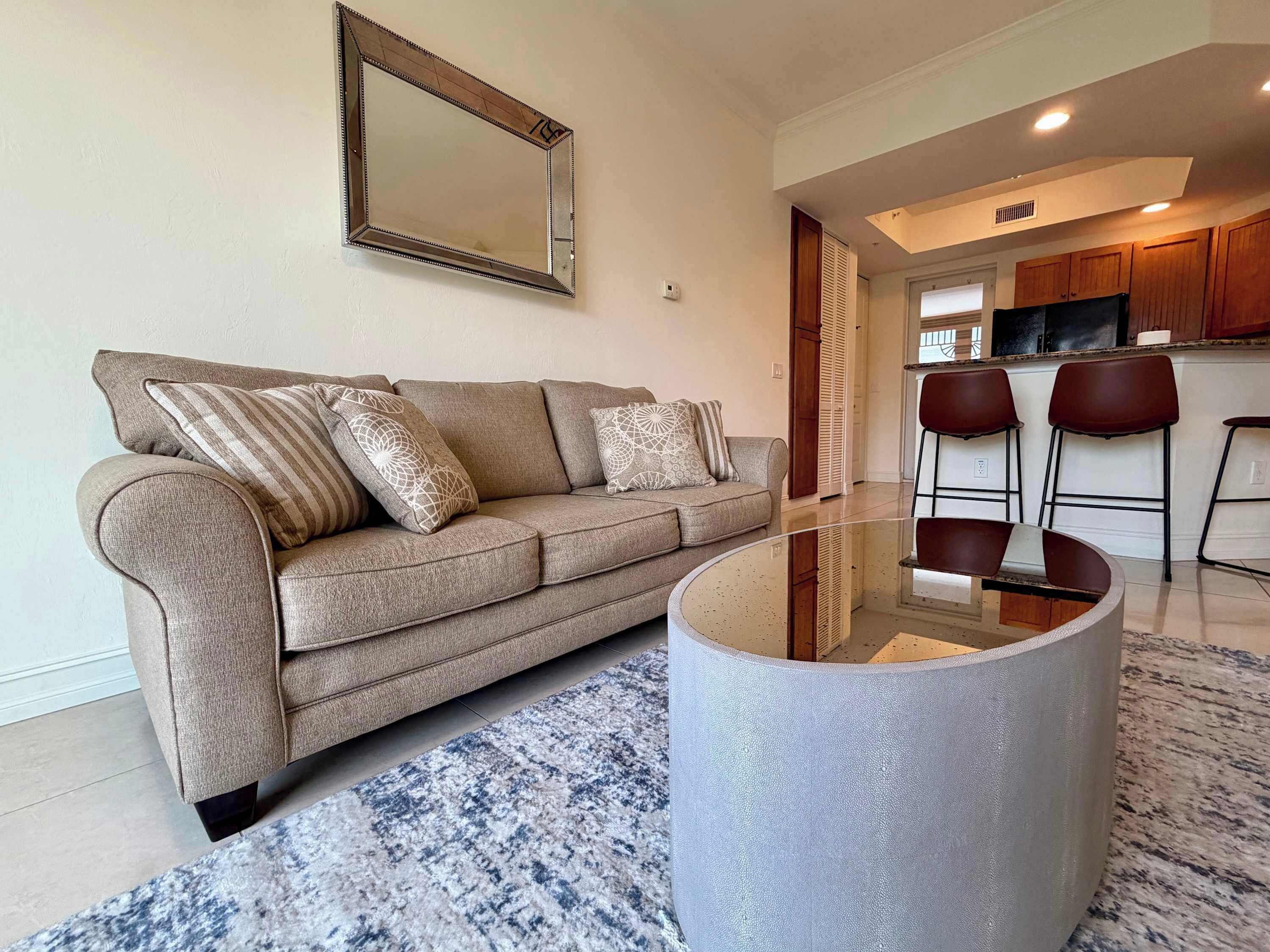 A living room with a sofa, a coffee table, and a large mirror.