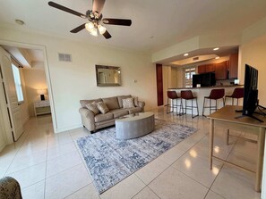 A modern living room with a sofa, coffee table, and a dining area with a TV. - Just listed: Bonita Haven – Beach Gear – Near the Gulf (Bonita Springs)