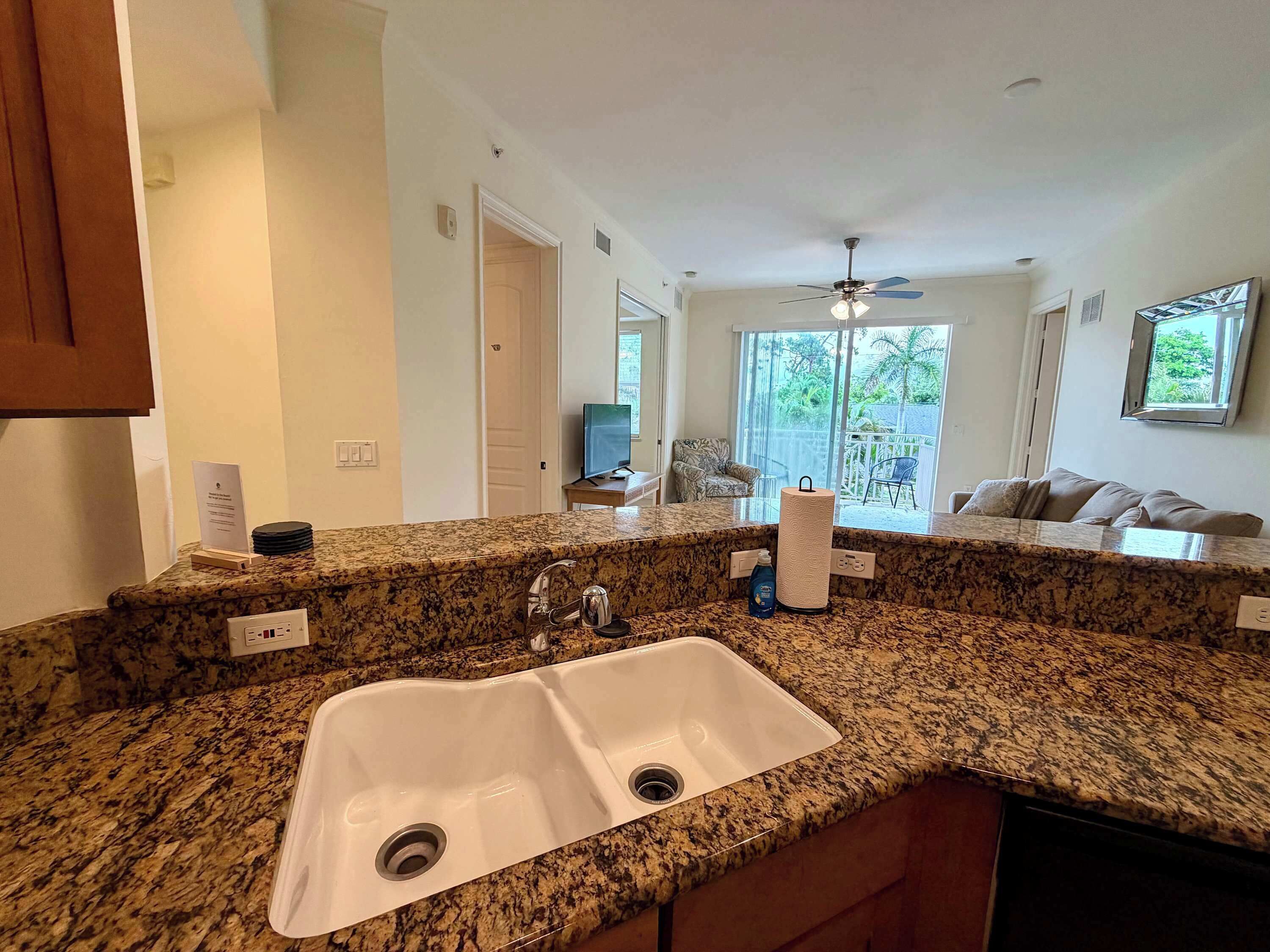 A kitchen with granite countertops, a double sink, and a ceiling fan.