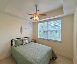 A bedroom with a bed, a ceiling fan, a window with blinds, and a wall-mounted decoration. - Just listed: Bonita Haven – Beach Gear – Near the Gulf (Bonita Springs)