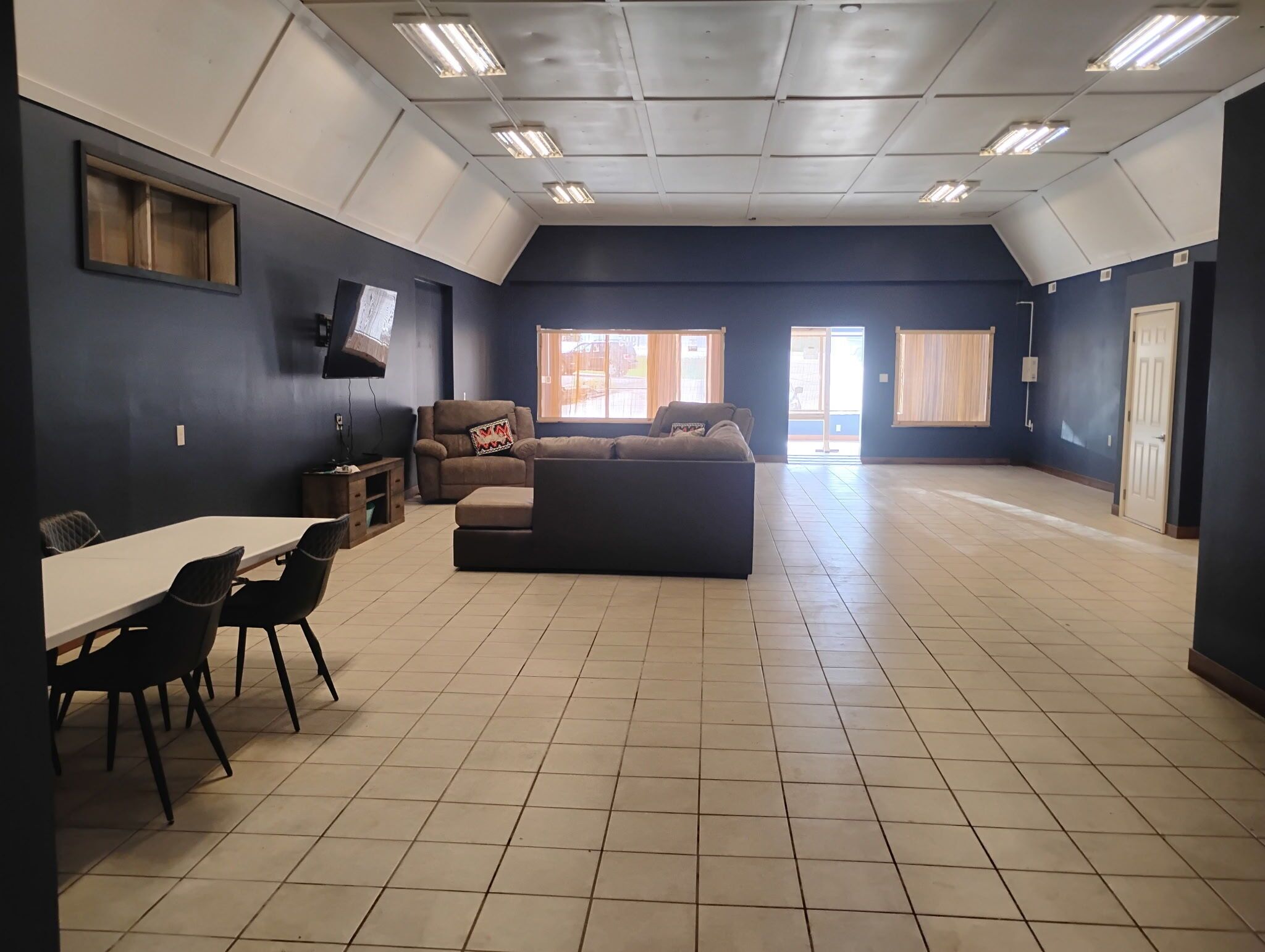 A spacious room with a dining table, chairs, a sofa, and a television.