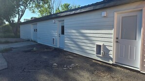 A single-story building with a garage door, a small window, and a door with a window above it. - Black Hills Barking Bunkhouse - Remodeled bldg with all amenities and 3 RV sites (Belle Fourche)